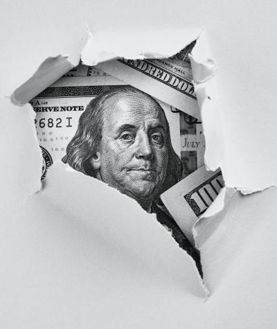 A $100 bill seen through torn paper.
