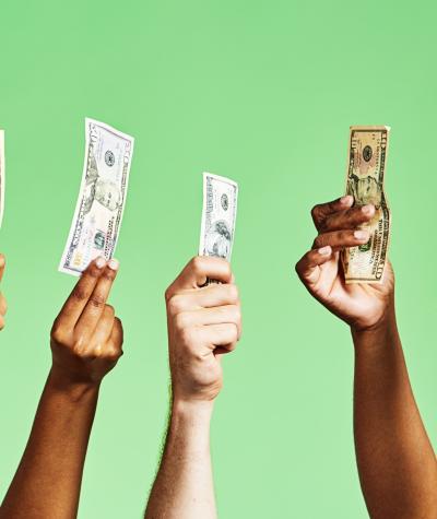 A row of people's hands holding up money against a green background