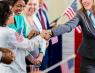 A woman shakes hands with a group of other women holding American flags