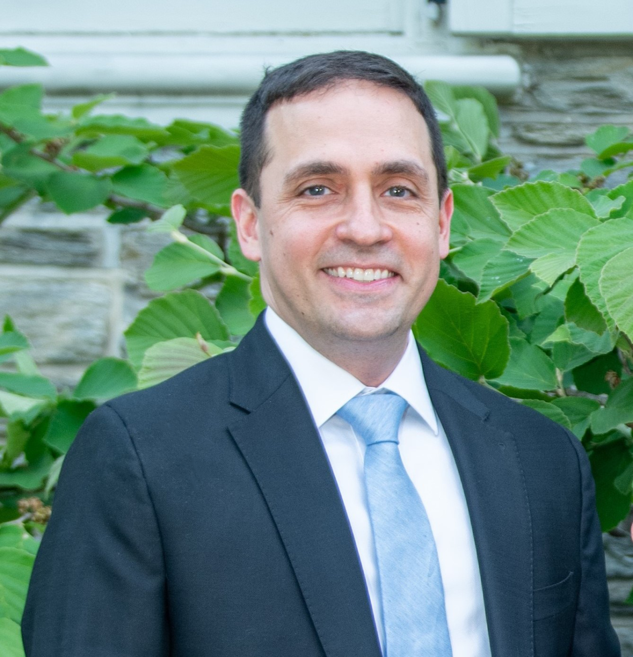 Headshot of Adav Noti, CLC's new executive director. He's wearing a suit in front of some greenery.
