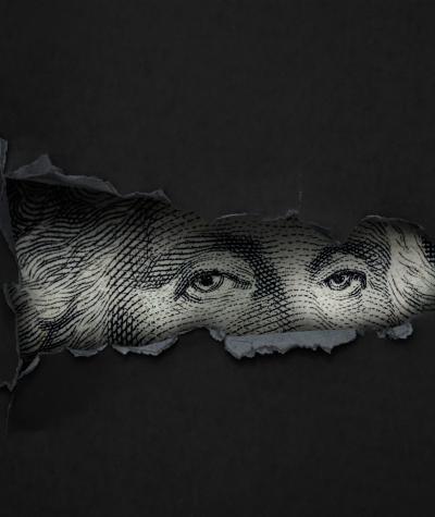 Eyes of George Washington from a one dollar bill peering through a torn black piece of paper