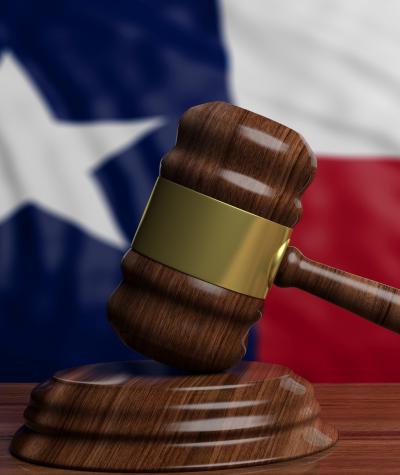 A gavel in front of the state flag of Texas.